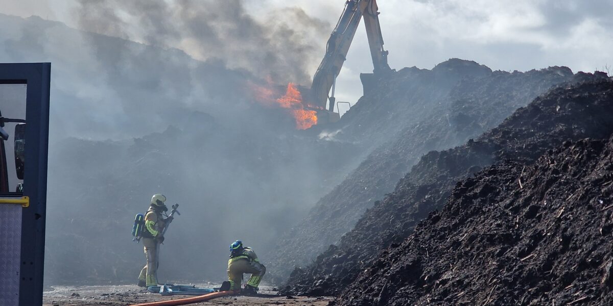 Flinke rookpluim bij groenrecycling langs N201 door brandende graafmachine